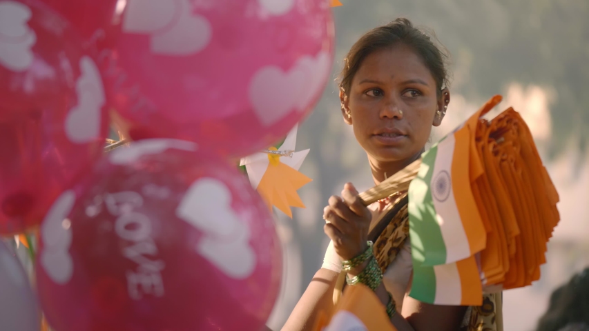 A poorunderprivileged woman female street vendor selling Indian tricoloured spin wheels on the road on the eve on Republic National day parade, Mumbai, India