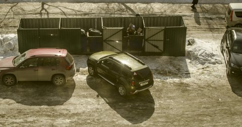 Russia, Novosibirsk, Circa 2020. Timelapse of a parking lot near garbage bins with standing and passing cars, pedestrians on a winter day.