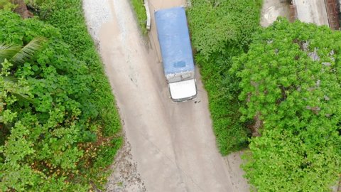Top view of road between trees as lorry driving off with a load - static