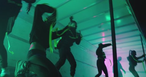 Footage of professional swag, freestyle or hip hop female dancers . Stylish young masked girls dancing inside colorful truck, car trailer . Dancer's team, group of six girls . Shot on ARRI ALEXA .