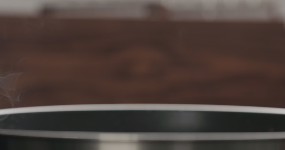 Slow motion man hand moving chicken fillet in pan with wood spatula closeup