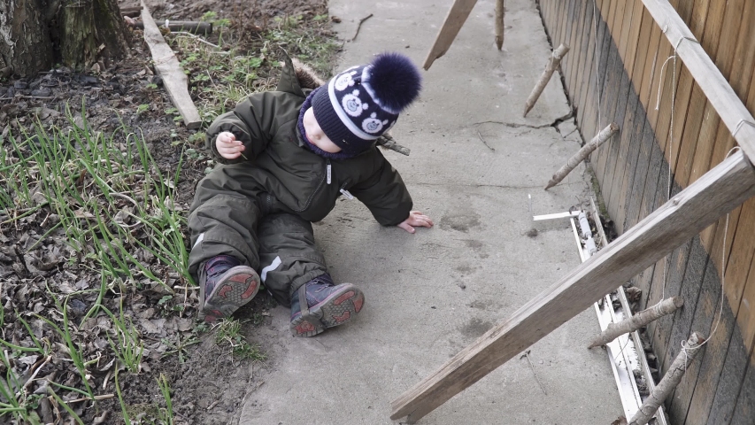 Baby boy in the country staggers a wooden frame for drawing even beds in the garden