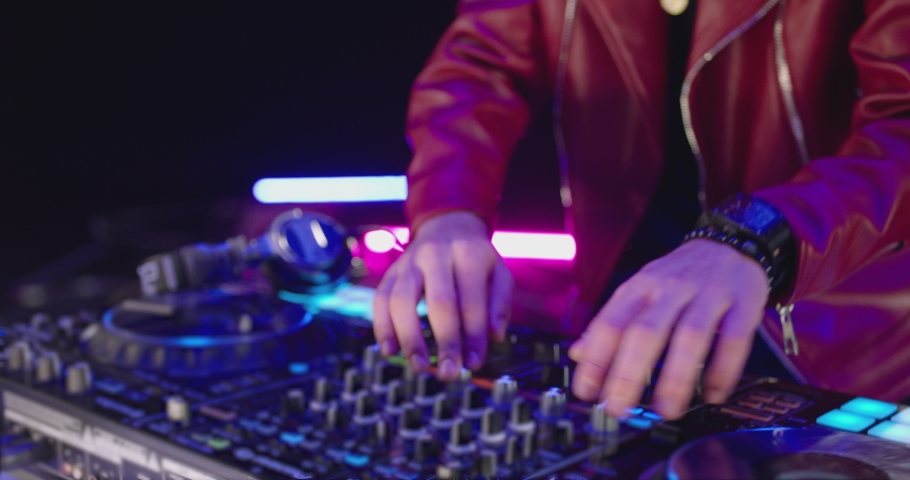 Close-Up of Dj Mixer Controller Desk in Night Club Disco Party. DJ Hands touching Buttons and Sliders Playing Electronic Music . Amazing Close Up of DJ Hands Mixing and Scratching Music on Vinyl Plate Royalty-Free Stock Footage #1050758326
