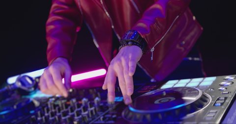 Close-Up of Dj Mixer Controller Desk in Night Club Disco Party. DJ Hands touching Buttons and Sliders Playing Electronic Music . Amazing Close Up of DJ Hands Mixing and Scratching Music on Vinyl Plate