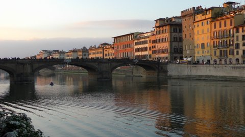 FLORENCE, ITALY - FEBRUARY 24, 2020: Motor boat under the Holy Trinity Bridge (Italian: Ponte Santa Trinita) on the Arno River in Florence.