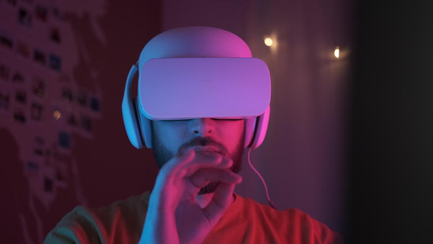 Neon light. Handsome man wearing virtual reality headset. Augmented Reality. Creative man touch something using modern 3D vr glasses indoors. Freelancer student playing using VR glasses. Closeup 4K Royalty-Free Stock Footage #1050758941