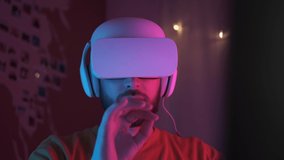 Neon light. Handsome man wearing virtual reality headset. Augmented Reality. Creative man touch something using modern 3D vr glasses indoors. Freelancer student playing using VR glasses. Closeup 4K