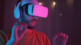 Neon light. Handsome man wearing virtual reality headset. Augmented Reality. Creative man touch something using modern 3D vr glasses indoors. Freelancer student playing using VR glasses. Closeup 4K - Powered by Shutterstock - Get 15% off with code: PIKWIZARD15
