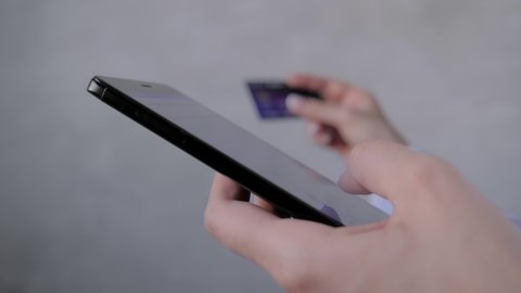Close up: woman using black smartphone mobile device, holding credit card, buying goods or ordering online - slow motion. E-commerce, sale, consumerism, electronic payment, online shopping concept