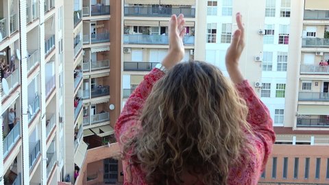 Huelva, Spain - April 19, 2020: Woman clapping on balcony as every day, at 8 PM.  Epidemic period of deadly coronavirus.