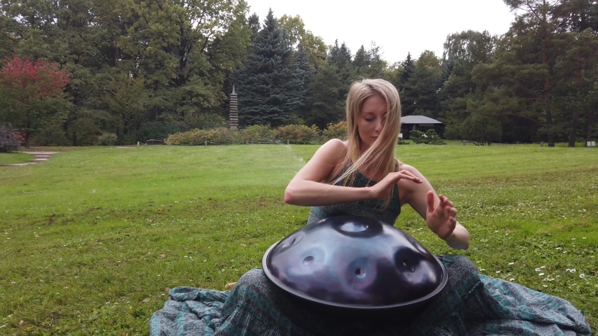Musician rehearsing a hang game in autumn green garden