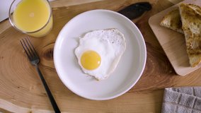 Fried egg in a white plate.  Sunny side with yolk up. Elegant video in 4K, ideal for food and recipe videos. Download the preview for free. Shot with a RED camera.