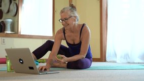 Mature woman smiles and waves at computer talking to her therapist regarding myofascial deep tissue massage with lacrosse ball.