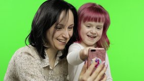 Cute funny little kid girl having fun with mom enjoy using modern gadget smart phone looking at mobile screen laughing making conference call in app, watching social media video. Chroma key