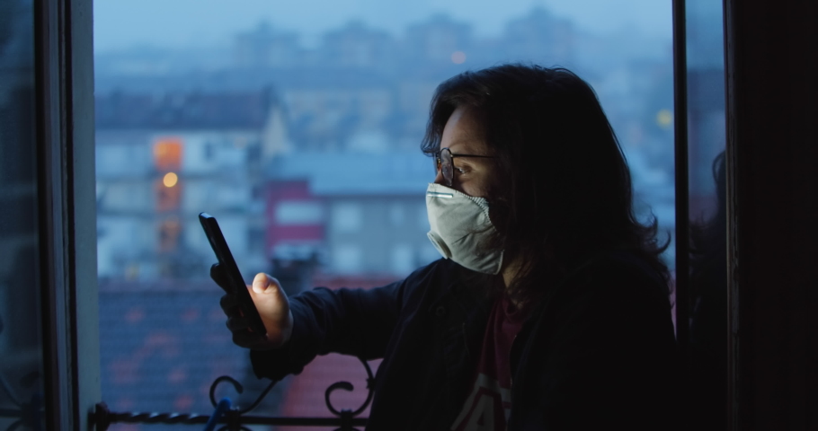  Quarantine in Europe. Girl has a conversation online using a video call. A person holding a phone in front of a window