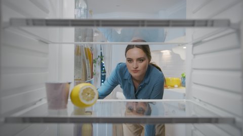 Beautiful Young Woman Opens Fridge Door, Checks Out that it's Empy and Closes Door with Disappointment. Point of View POV from Inside of the Kitchen Refrigerator