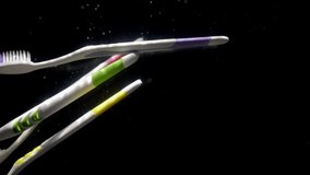Super slow motion white toothbrushes falling into the water scattering bubbles on a black background, close up. - Powered by Shutterstock - Get 15% off with code: PIKWIZARD15