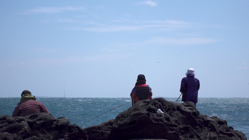 
People are catching fish on the rocks.Beautiful background of blue sky and blue sea.