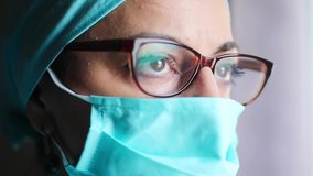 Close up video of a woman doctor wearing a surgical mask and glasses, in natural light.