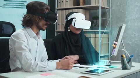 international business meeting, man and muslim woman in virtual reality glasses exploring the futuristic hologram layout of a business center, demonstration of the architecture using augmented reality