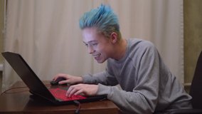 emotional gamer paying onlline video game, shouted to team, excited gamer with blue hair, clor hair teenager
