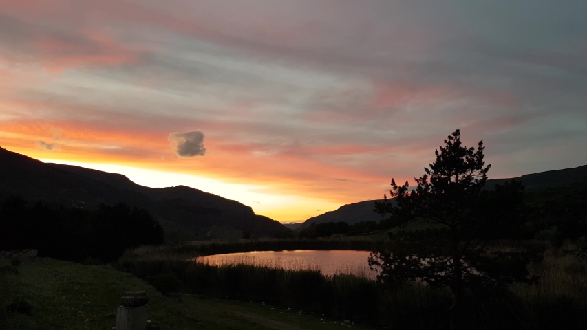 4K video, orange sunset or sunrise over a lake in the mountains