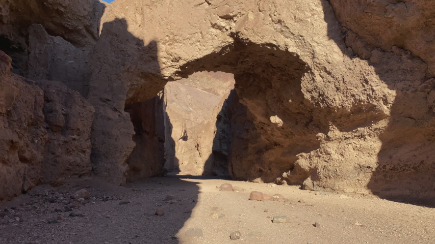 Walking along the canyon path toward the Natural Bridge formation at Death Valley National Park, California. Tracking shot inward.