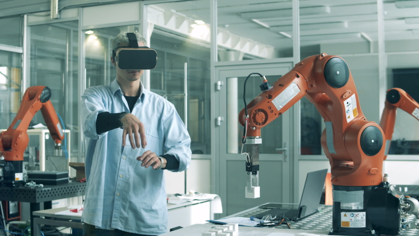 Engineer in VR-glasses is manipulating a bionic device. High school students studying robotics technologies at university lab. Royalty-Free Stock Footage #1050826246