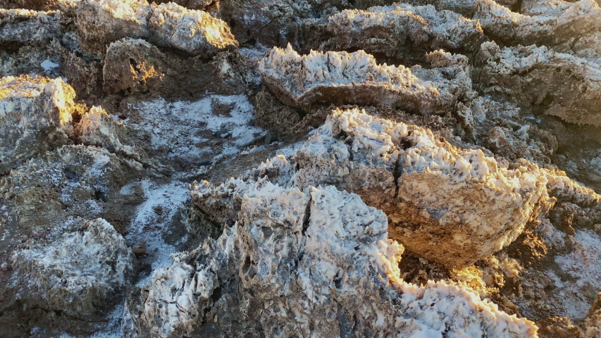 Close-up of rough salt formations glowing in golden sunset light at Devils Golf Course in Death Valley National Park, California. Camera slides left to right.