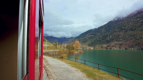 Cinematic landscape shot of reflection from train window. Inspiring travel destination for world traveling explorers. Switzerland bernina train, oldest mountain railway in the world. Autumn views