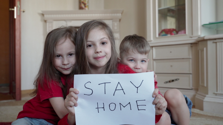 Family stay at home concept. Three children holding sign saying stay at home for virus protection and take care of their health from COVID-19. Royalty-Free Stock Footage #1050842218