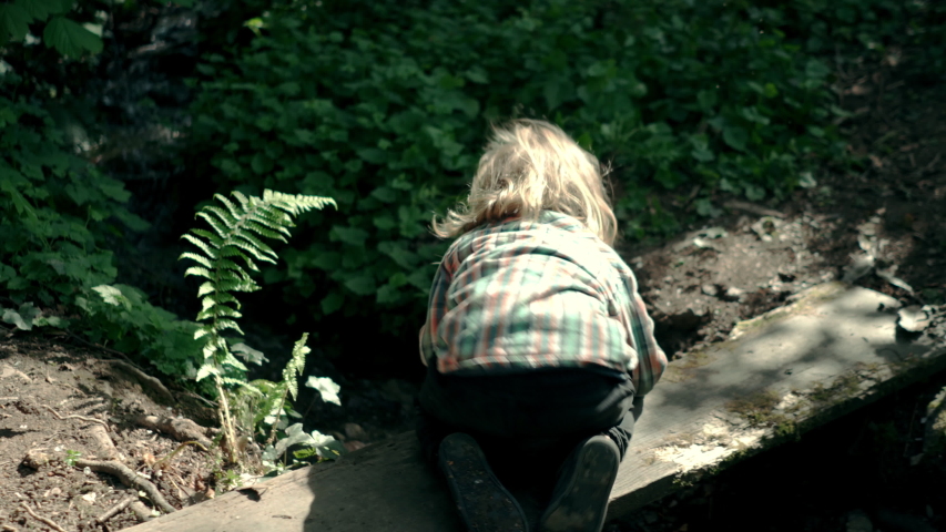 A little boy is playing with the water in a brook