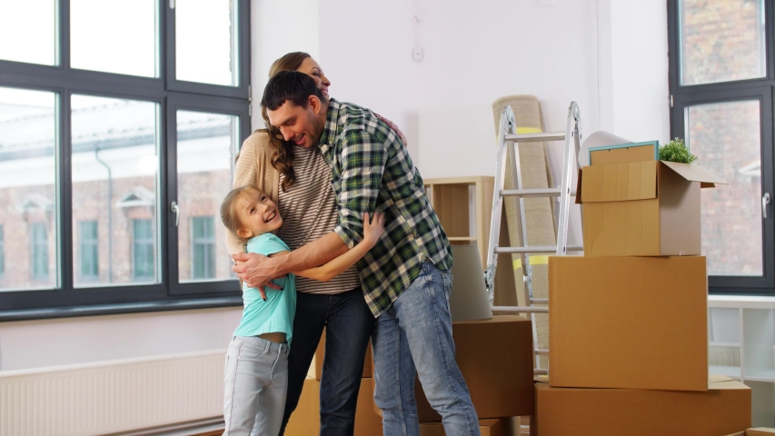 Mortgage, family and real estate concept - happy mother, father and little daughter with stuff in boxes moving to new home and hugging | Shutterstock HD Video #1050870100