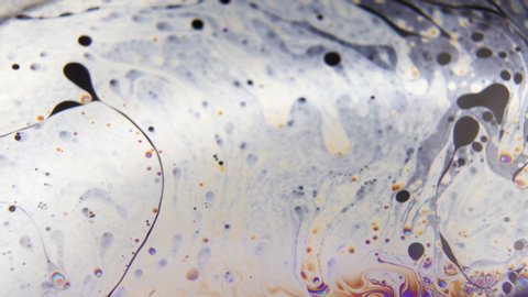 Grey liquid moving around creating colorful bubbles abstract background