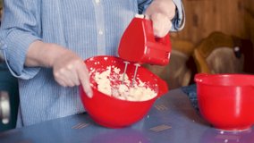 Mixing dough in bowl with motor mixer. Woman preparing a dough. Cooking cake. Close up video of a chef using an electric mixer. Social distancing.