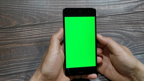 Close-up of man hands using smartphone with green screen. Close up video of man's hands reading news and looking social media web pages on mobile phone. Chroma key. Vertical