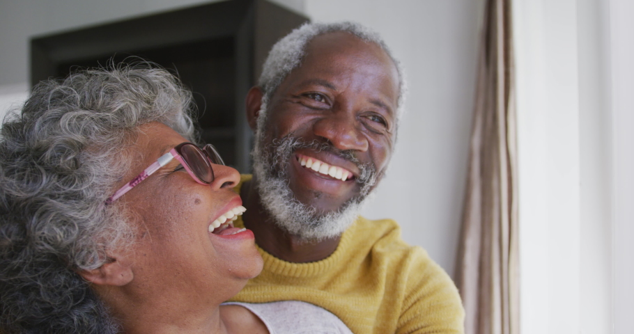 A senior African American couple spending time at home together, social distancing and self isolation in quarantine lockdown during coronavirus covid 19 epidemic, embracing, smiling in slow motion