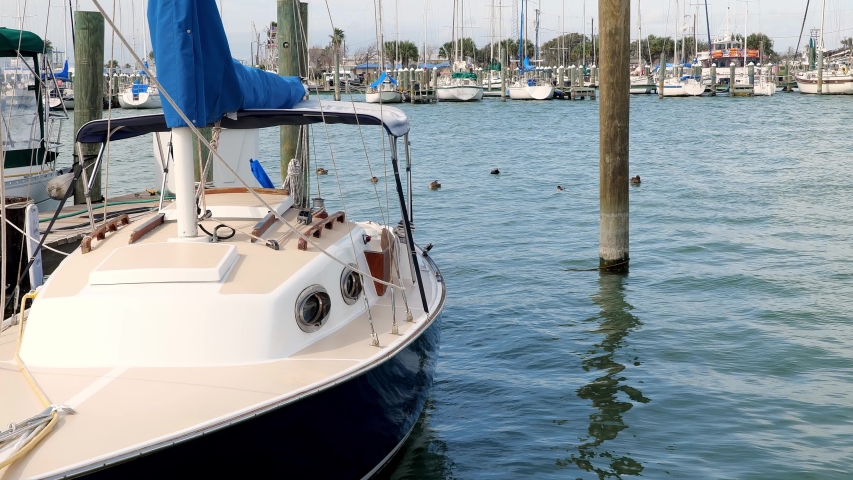 Sailboat tied to the dock in marina in Rockport, Texas with ducks swimming in water behind the boat.
