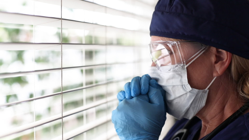 Stressed Doctor or Nurse On Break Praying At Window Wearing Face Mask and Protective Glasses. Royalty-Free Stock Footage #1050901897
