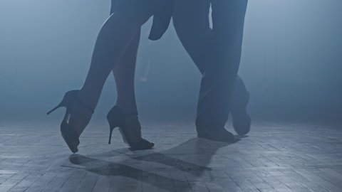 Legs of tango dancers in dark smoky studio. Woman goes to man. Woman legs on heels. Close-up shot in 4K, UHD