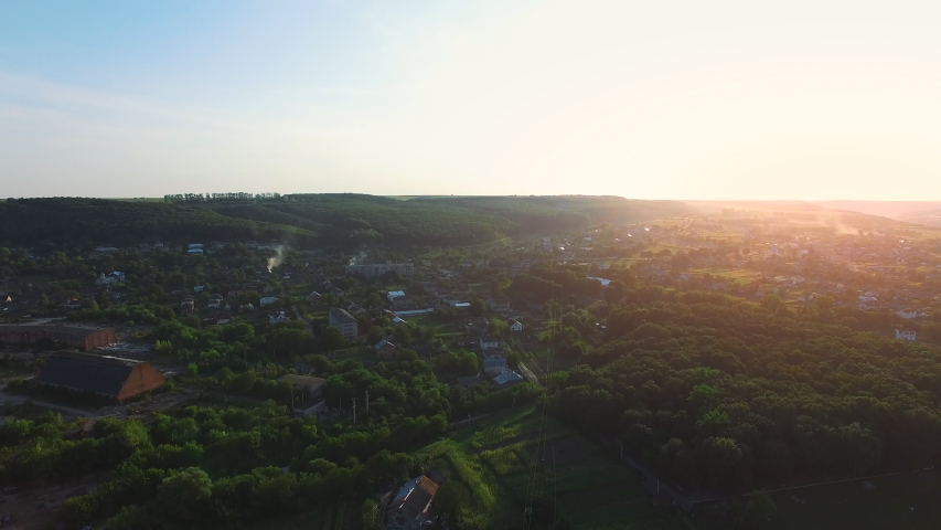 Picturesque village sinking in dense greenery on a sunset day lost between trees.