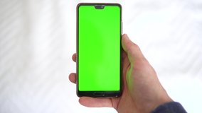 Person holds phone with editable greenscreen. Top-down pov shot of white male holding smartphone.