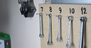 Slow panning clip of organized wrenches hanging on a board in a workshop. tools in a workspace in a garage