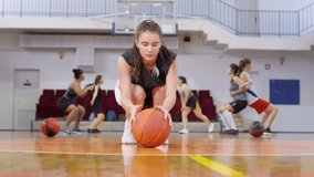 Young female athlete in sports uniform doing push ups with basketball and looking at camera while training on court - Powered by Shutterstock - Get 15% off with code: PIKWIZARD15
