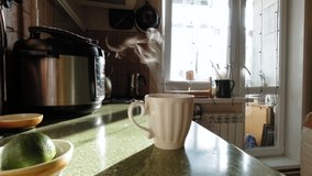 Woman hand pour coffee in mug in home kitchen. Steam come from cup. Sunny morning. Work out of home. Coffee break. Stock slow motion video.
