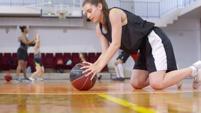 Young female athlete doing push ups with basketball and then sticking out her tongue and falling down on court while getting tired after workout - Powered by Shutterstock - Get 15% off with code: PIKWIZARD15