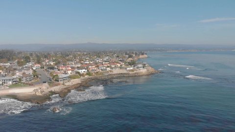 Aerial shot featuring the pacific shoreline and coastal homes of Santa Cruz on a sunny day with clear blue skies. 