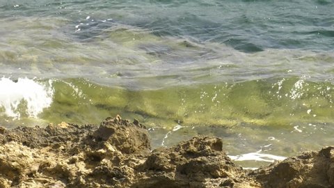 Waves of clear water washing onto jagged rocks, mediterranean sea