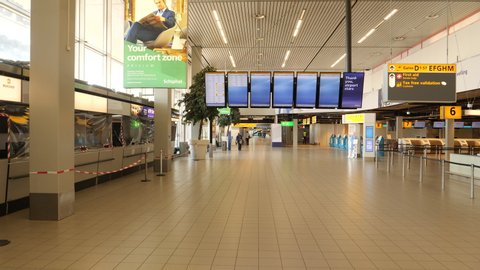 Amsterdam, Netherlands, April 2020. Deserted departure terminal with maintenance worker at Schiphol airport during corona crisis.