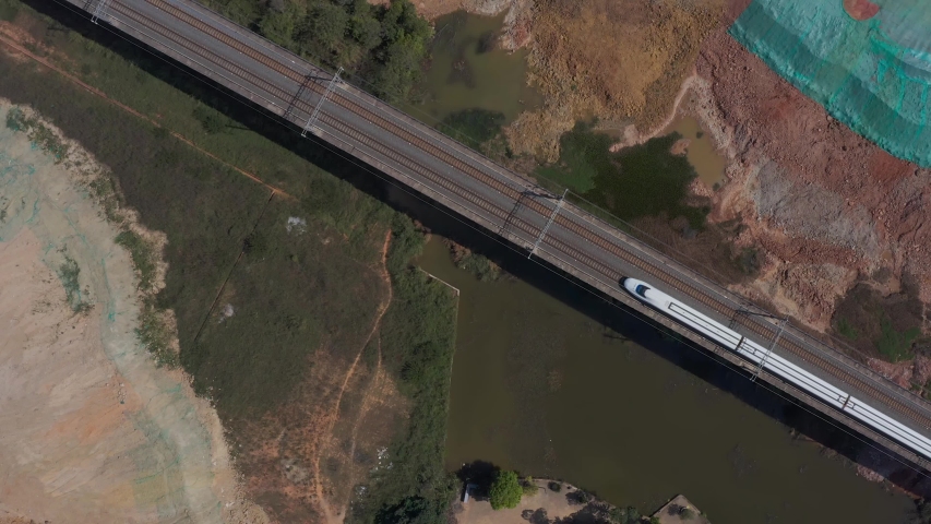 Aerial shot of white bullet high-speed train traveling on land in China